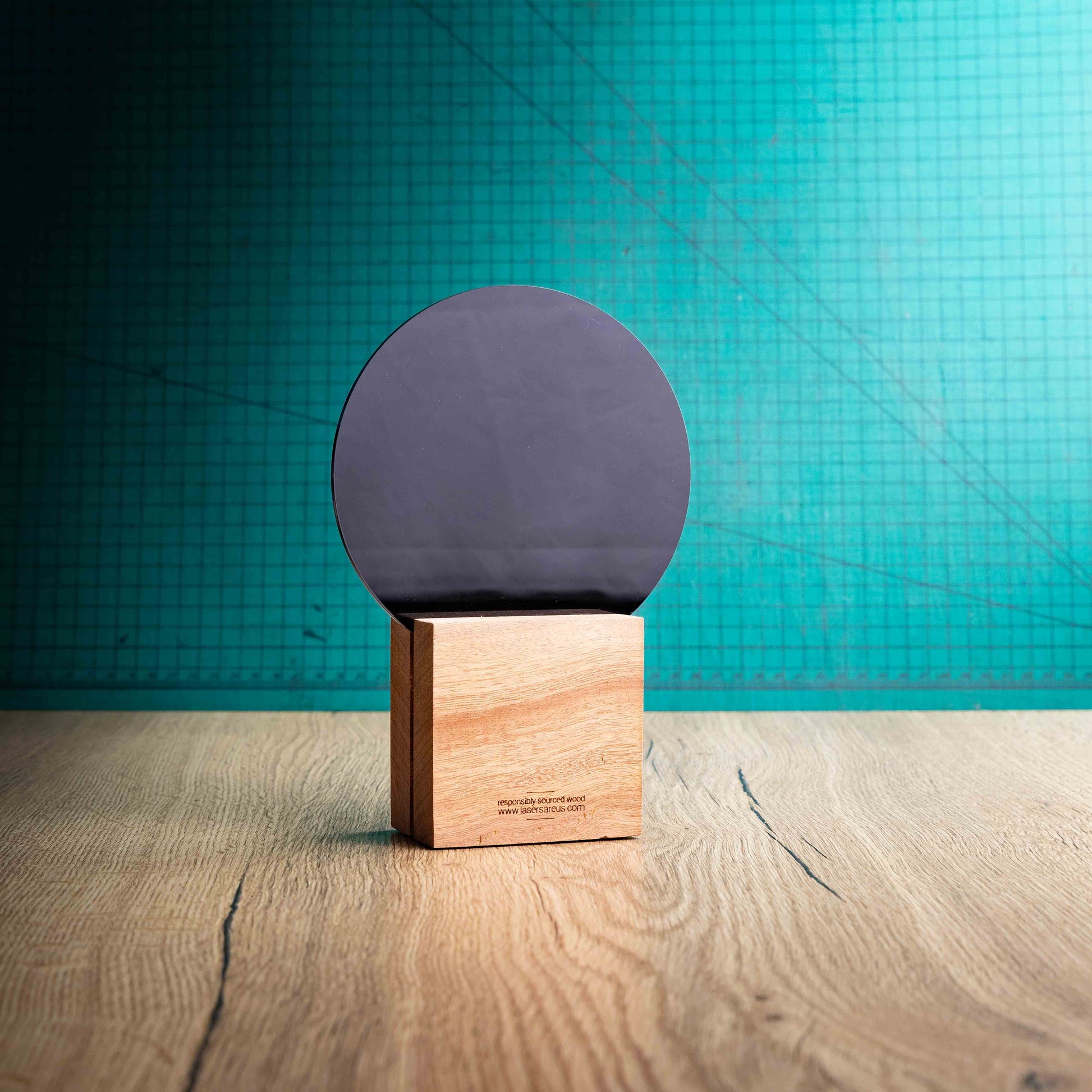 The back of the Legacy Award, an Eco-friendly wooden trophy with 'responsibly sourced wood' text and www.lasersareus.com on a wooden surface.