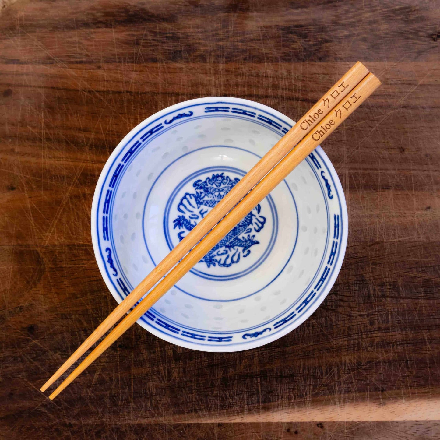 A pair of Japanese-style Chopsticks, colour light wood. The chopsticks are laser engraved and personalised with either a name or a phrase in English and are translated into either Chinese or Japanese.