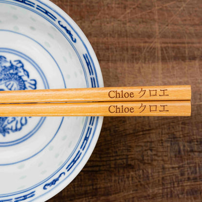 A pair of Japanese-style Chopsticks, colour light wood. The chopsticks are laser engraved and personalised with either a name or a phrase in English and are translated into either Chinese or Japanese.