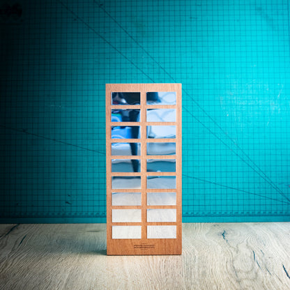 A rectangular wooden perpetual trophy with a grid of award plaques to engrave your winners names on, standing on a light wood surface against a teal background.