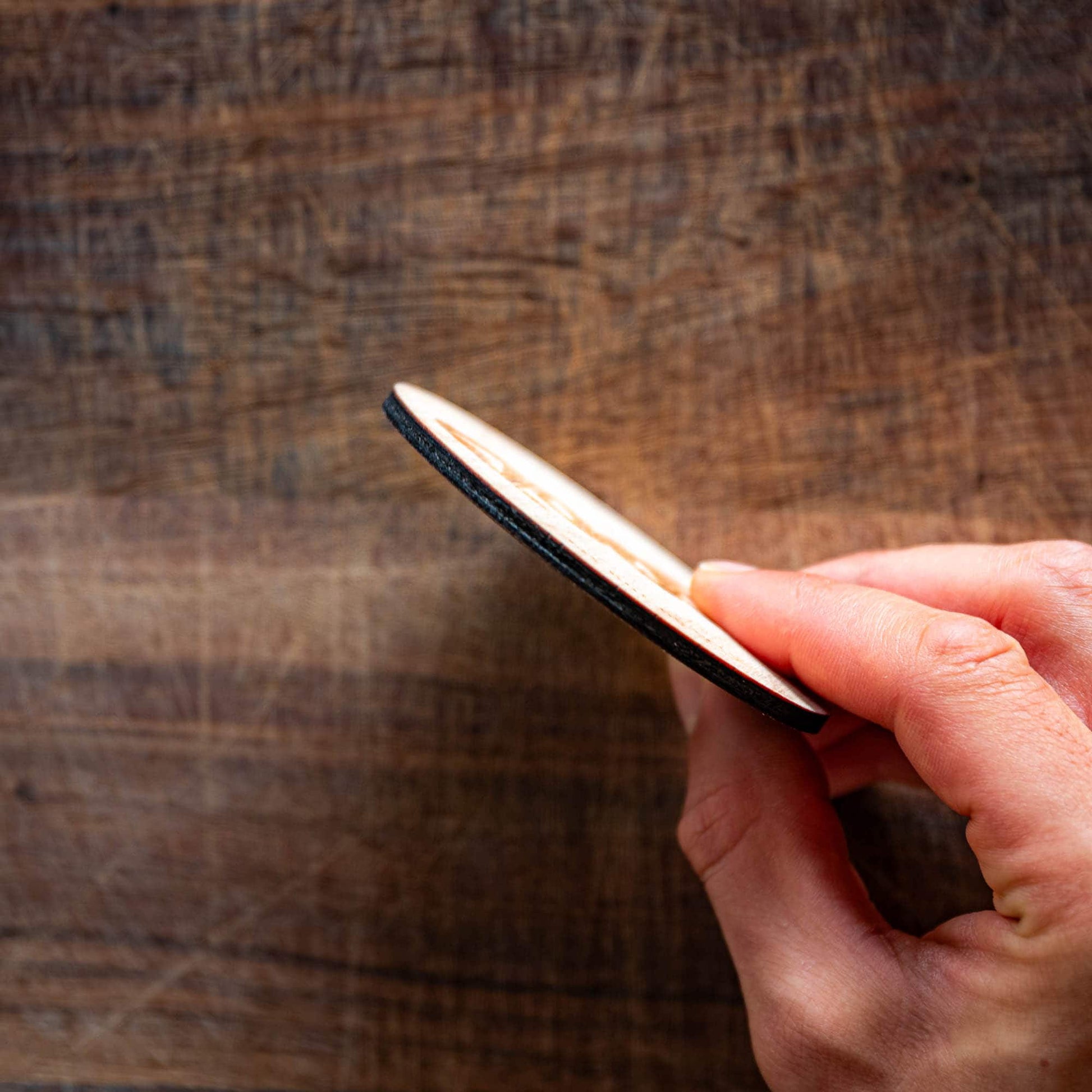 Showing the thickness of a wooden personalized coaster