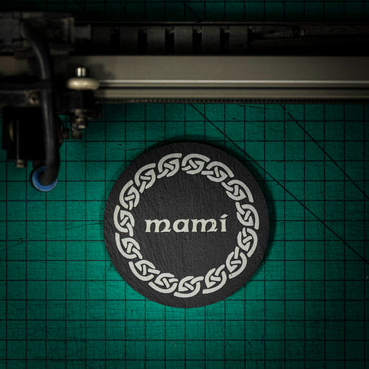 A Welsh slate coaster laser engraved with the welsh word for mummy, mami, inside a celtic knot