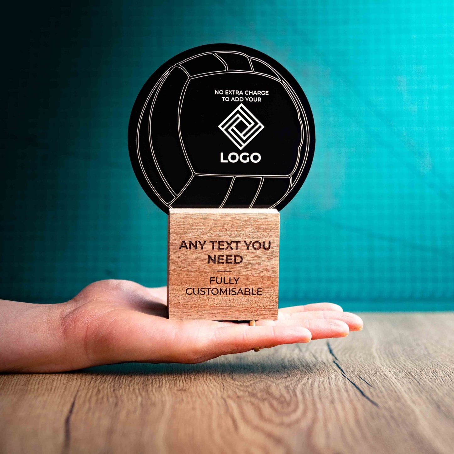 A large Netball trophy with custom text and logos, on an eco-friendly wooden base, with a black Perspex Netball mounted on top, featuring fully customisable areas for text and logos, being held to give a size perspective.