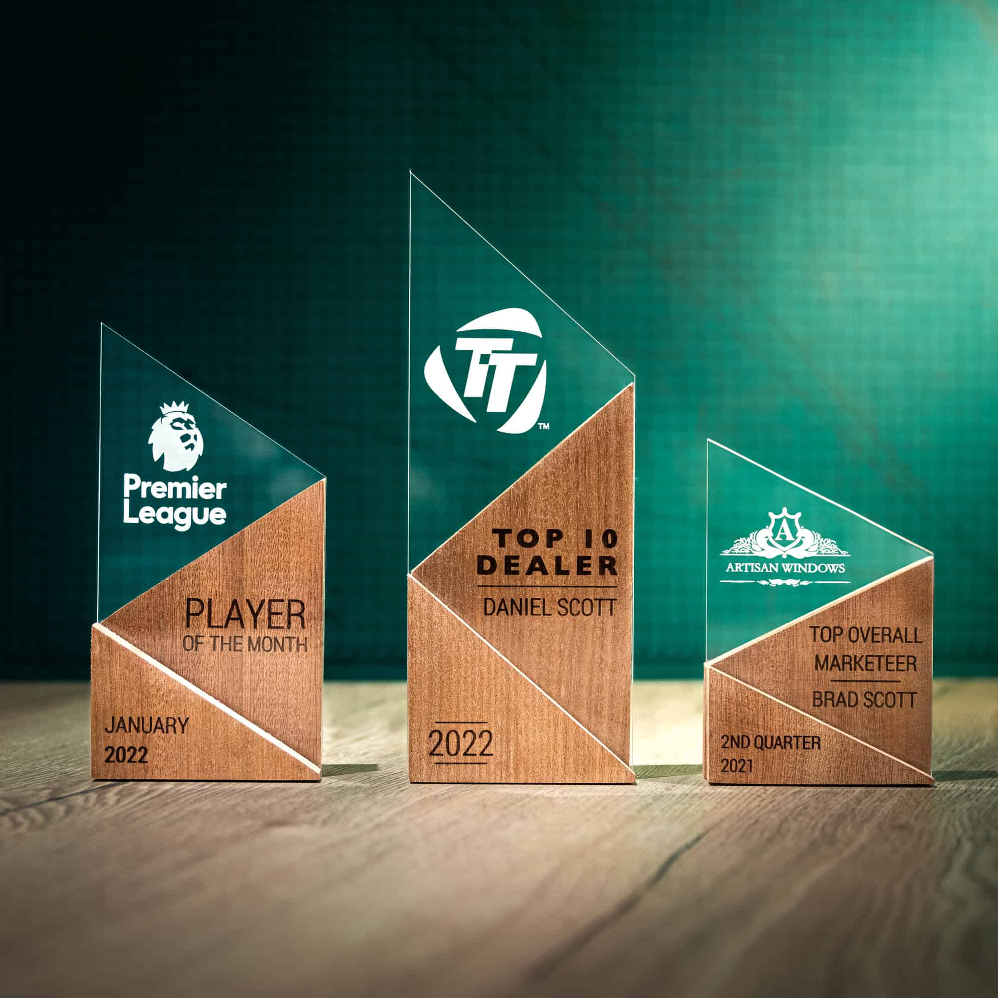 A small, medium and large personalised laser engraved perspex trophies with a wooden base