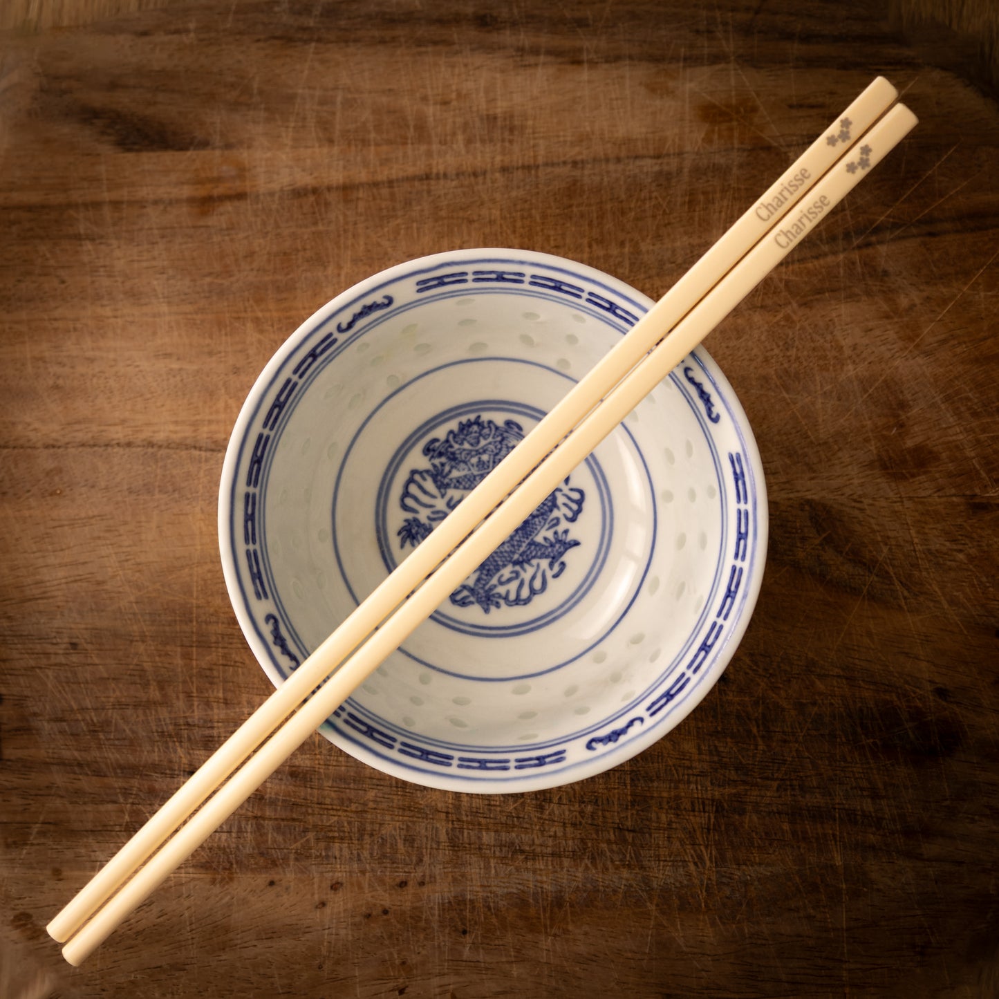 Cream coloured plastic melamine personalised chopsticks engraved with a name and three flowers.