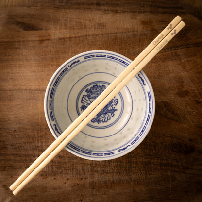 Cream coloured plastic melamine personalised chopsticks engraved with a name and three flowers.