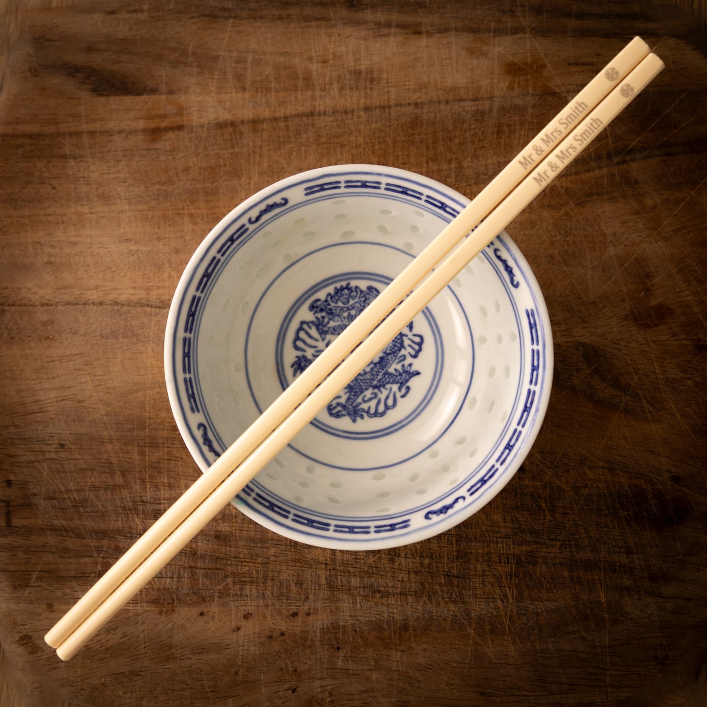 Cream coloured plastic melamine personalised chopsticks engraved for a wedding with a "Mr & Mrs Smith" and the Chinese symbol for double happiness in a circular pattern.