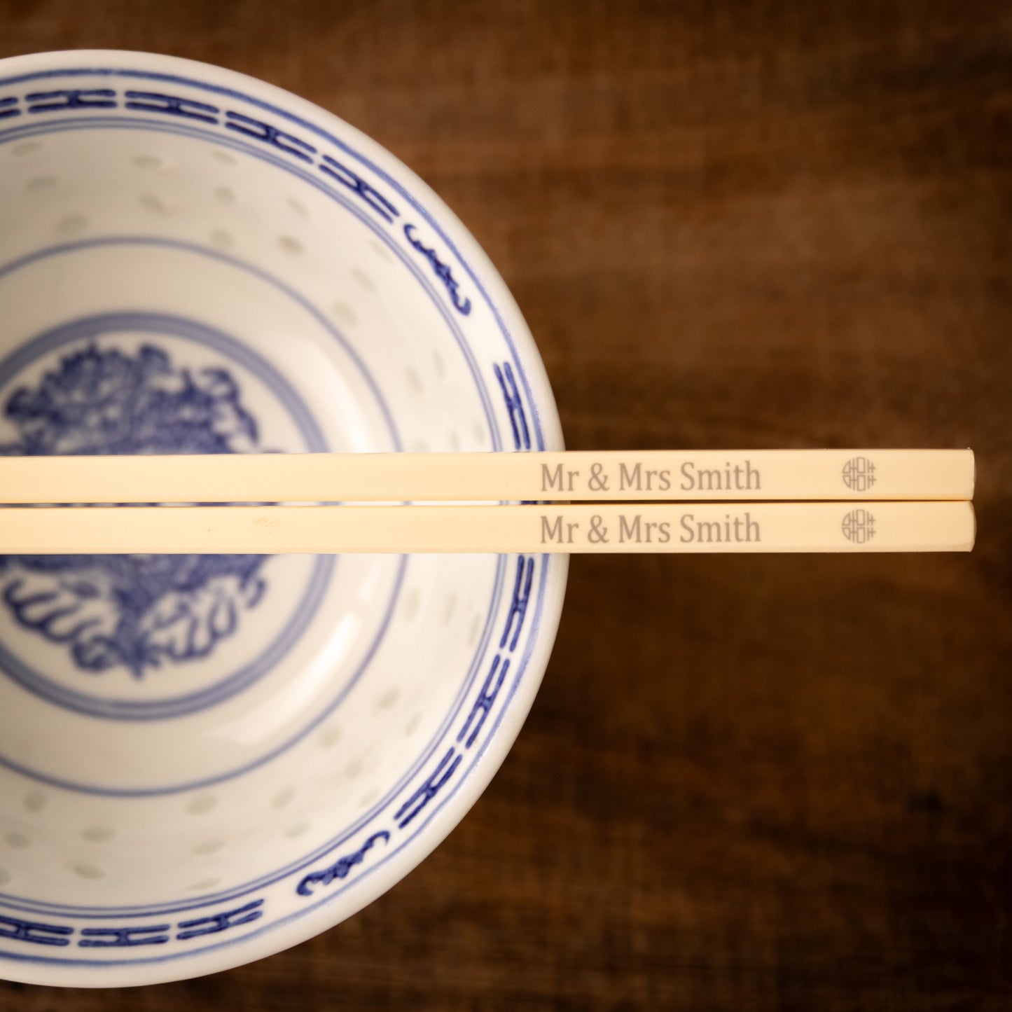 Cream coloured plastic melamine personalised chopsticks engraved for a wedding with a "Mr & Mrs Smith" and the Chinese symbol for double happiness in a circular pattern.