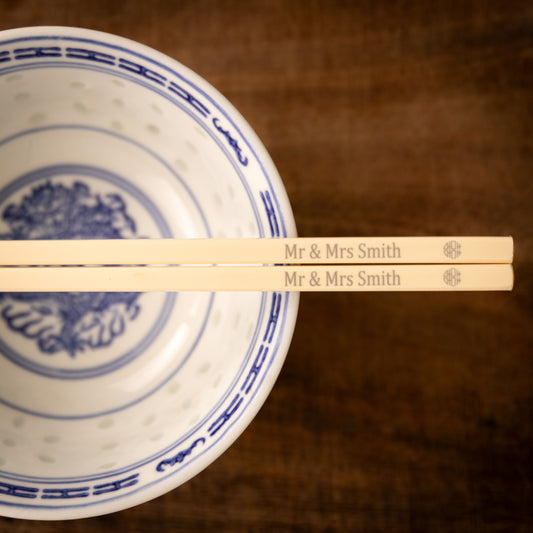 Cream coloured plastic melamine personalised chopsticks engraved for a wedding with a "Mr & Mrs Smith" and the Chinese symbol for double happiness in a circular pattern.