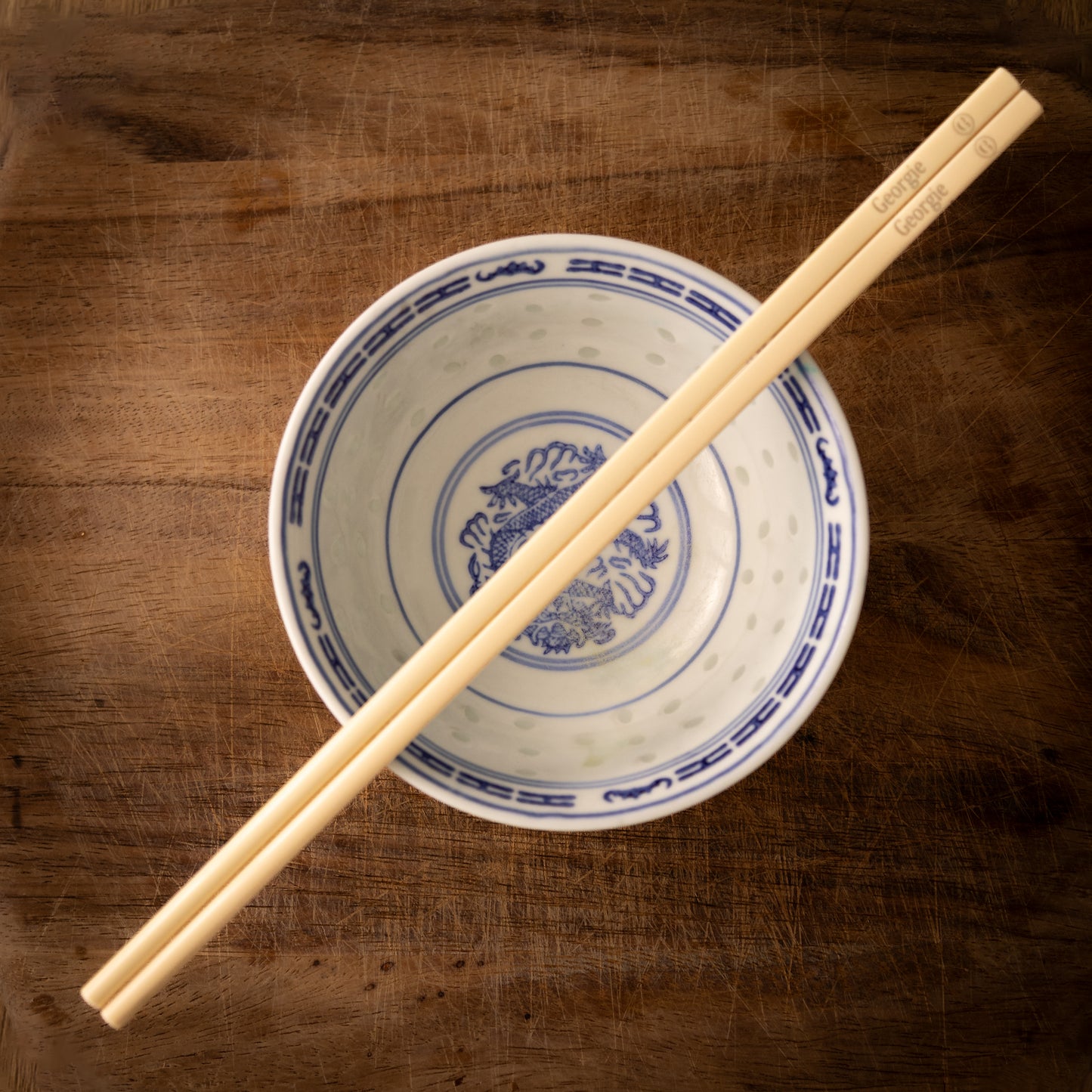 Cream coloured plastic melamine personalised chopsticks engraved with a name and a smiley face emoji.