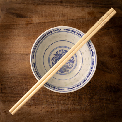Cream coloured plastic melamine personalised chopsticks engraved with a name and a smiley face emoji.