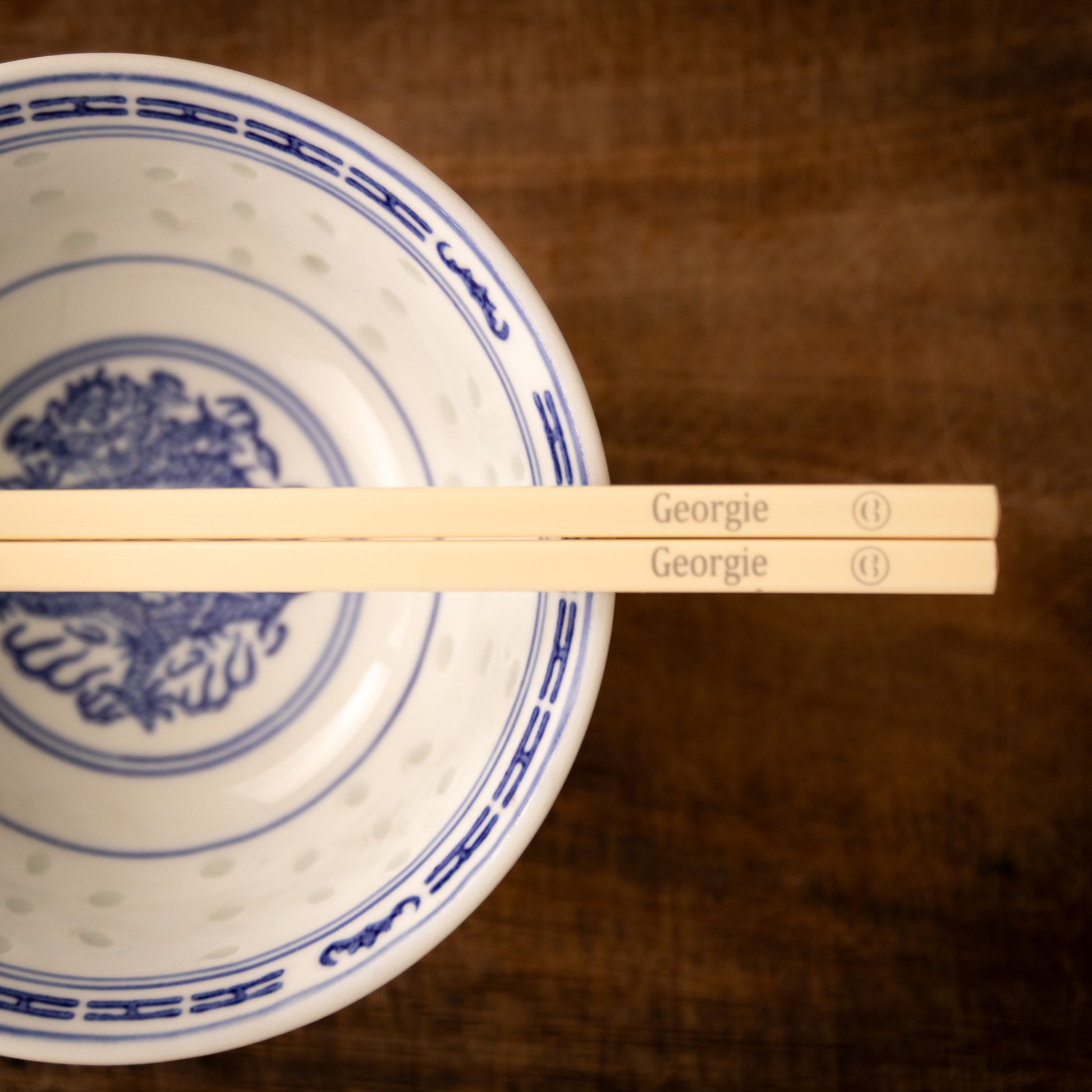 Cream coloured plastic melamine personalised chopsticks engraved with a name and a smiley face emoji.