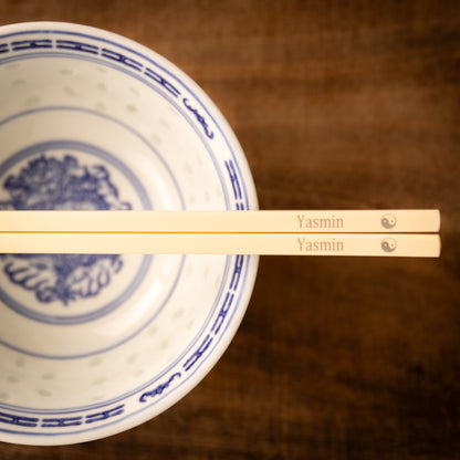 Cream coloured plastic melamine personalised chopsticks engraved with a name and the Ying Yang symbol.