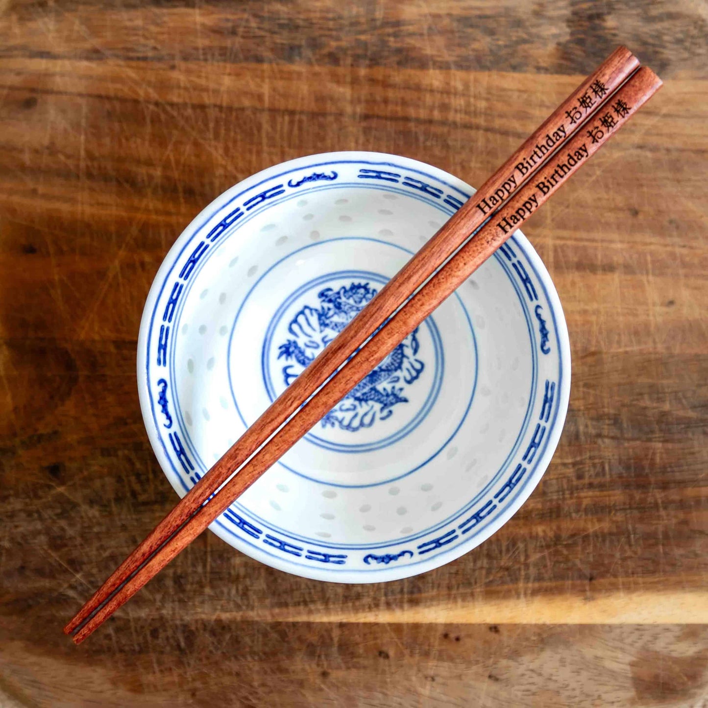 A pair of Japanese-style Chopsticks, colour rose wood. The chopsticks are laser engraved and personalised with either a name or a phrase in English and are translated into either Chinese or Japanese.