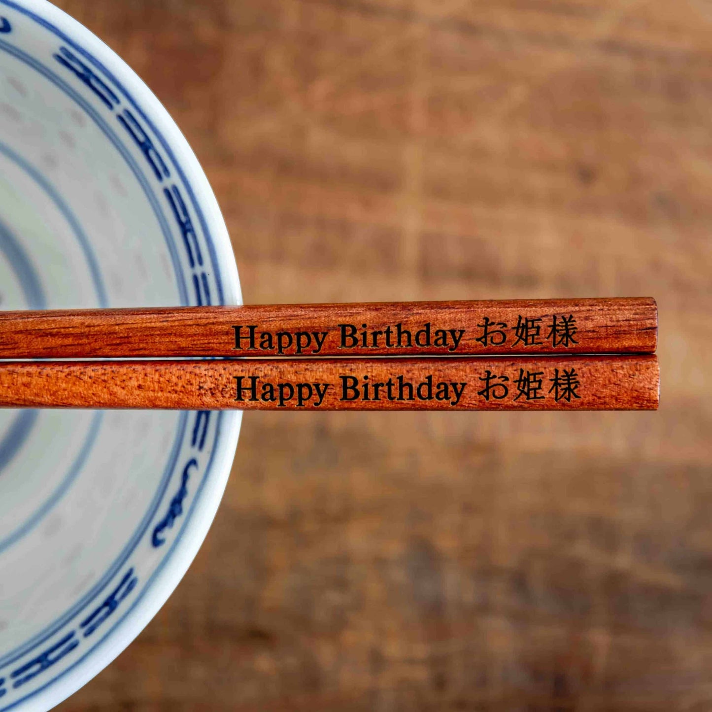 A pair of Japanese-style Chopsticks, colour rose wood. The chopsticks are laser engraved and personalised with either a name or a phrase in English and are translated into either Chinese or Japanese.
