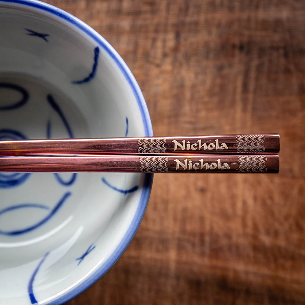 A pair of Chinese-style Metal Coloured Chopsticks - Rose Gold. Each pair is personalised with either a name or a phrase.