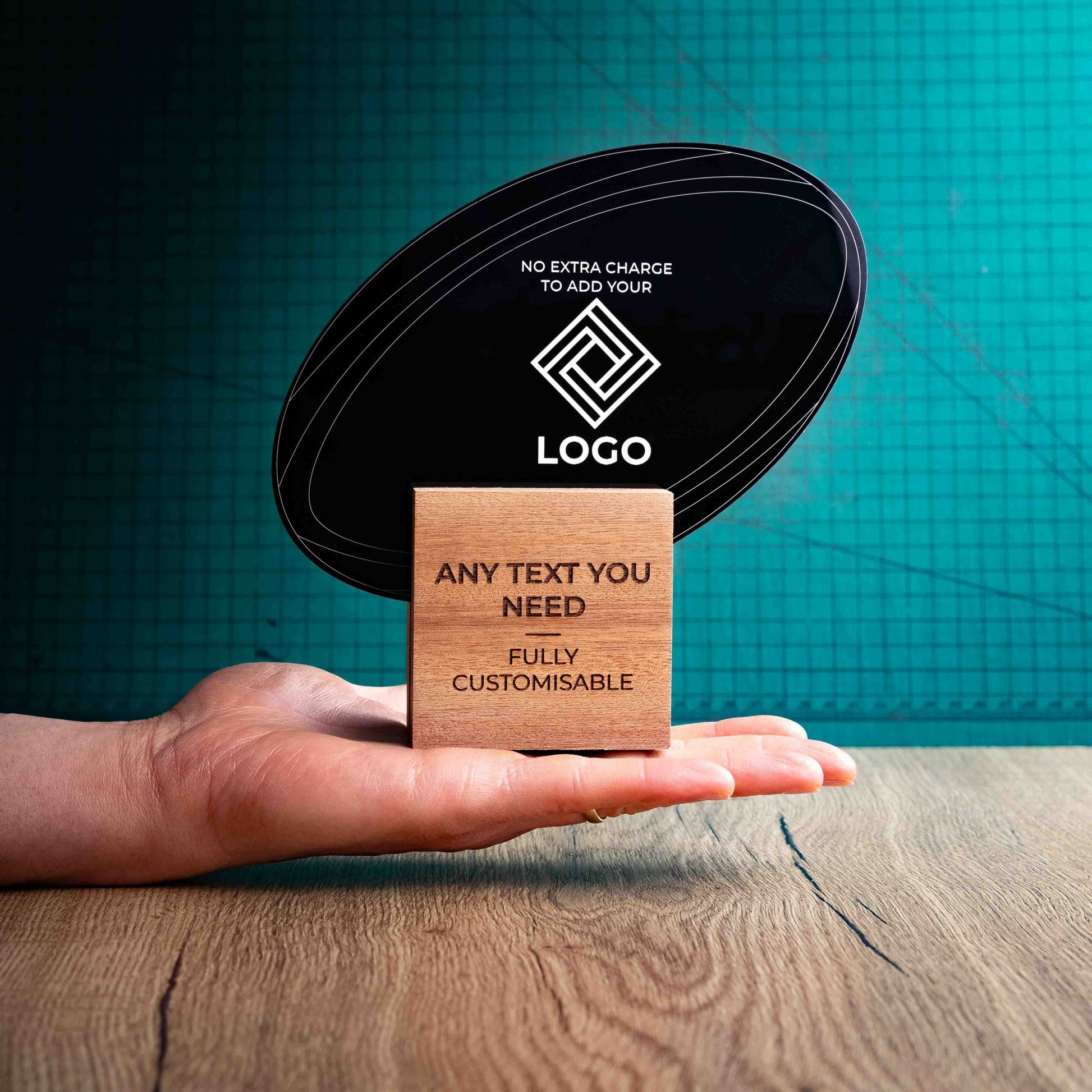 A hand holding a medium rugby award with custom text and logos, on an eco-friendly wooden base, with a black Perspex rugby ball mounted on top, featuring fully customisable areas for text and logos.