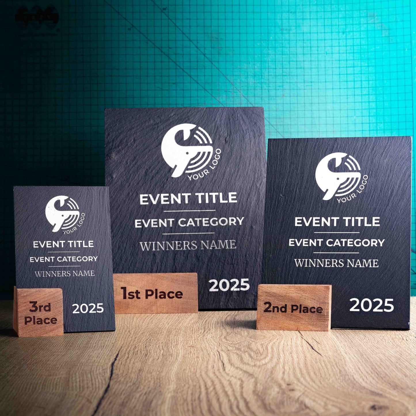 Three laser-engraved, eco-friendly, wooden and slate trophies called Solet. The Solet Award has a base made of two wooden pieces on either side of a square piece of Welsh Slate. The trophy is personalised with Event information and a logo. 
