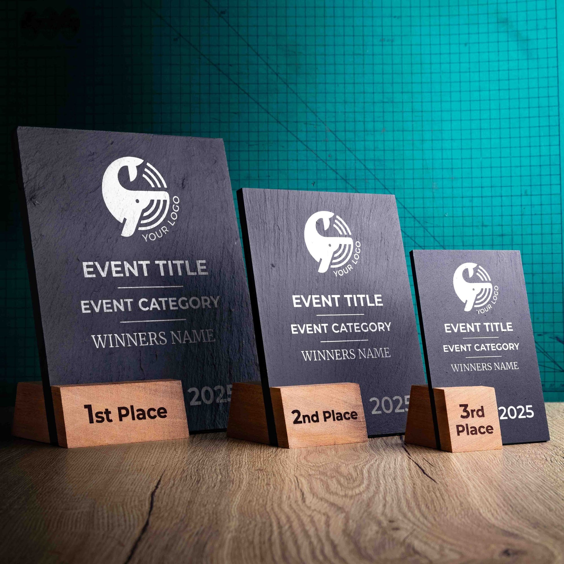 Three laser-engraved, eco-friendly, wooden and slate trophies called Solet. The Solet Award has a base made of two wooden pieces on either side of a square piece of Welsh Slate. The trophy is personalised with Event information and a logo. 