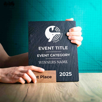 A large Solet Award, an eco-friendly, wooden and slate trophy. The Solet Award has a base made of two wooden pieces on either side of a square piece of Welsh Slate. The trophy is personalised with Event information and a logo. 