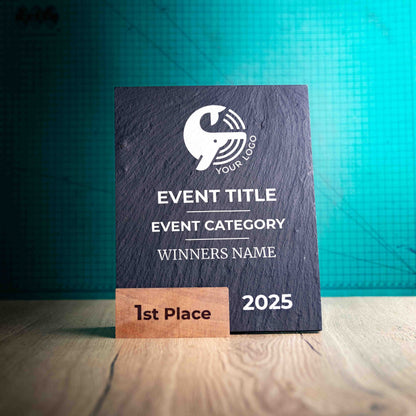 A large Solet Award, an eco-friendly, wooden and slate trophy. The Solet Award has a base made of two wooden pieces on either side of a square piece of Welsh Slate. The trophy is personalised with Event information and a logo. 