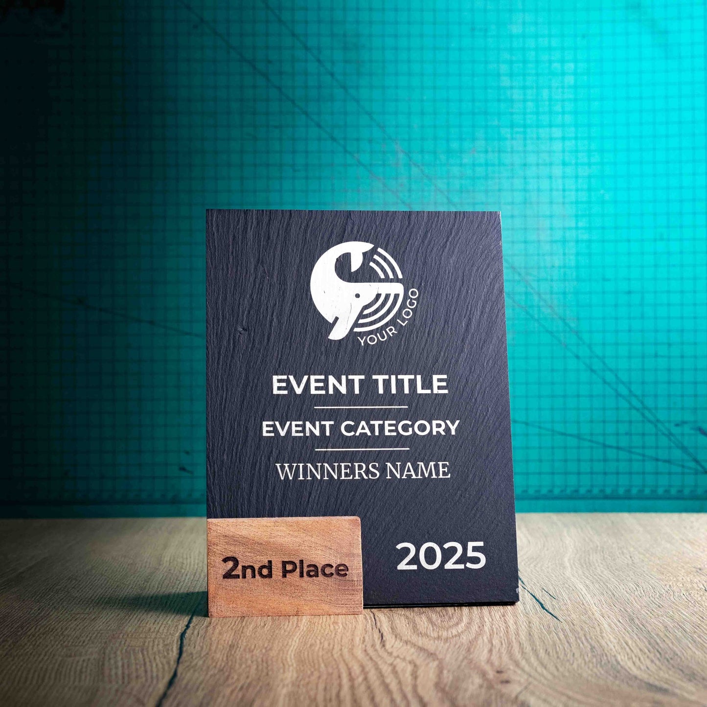 A medium Solet Award, an eco-friendly, wooden and slate trophy. The Solet Award has a base made of two wooden pieces on either side of a square piece of Welsh Slate. The trophy is personalised with Event information and a logo. 