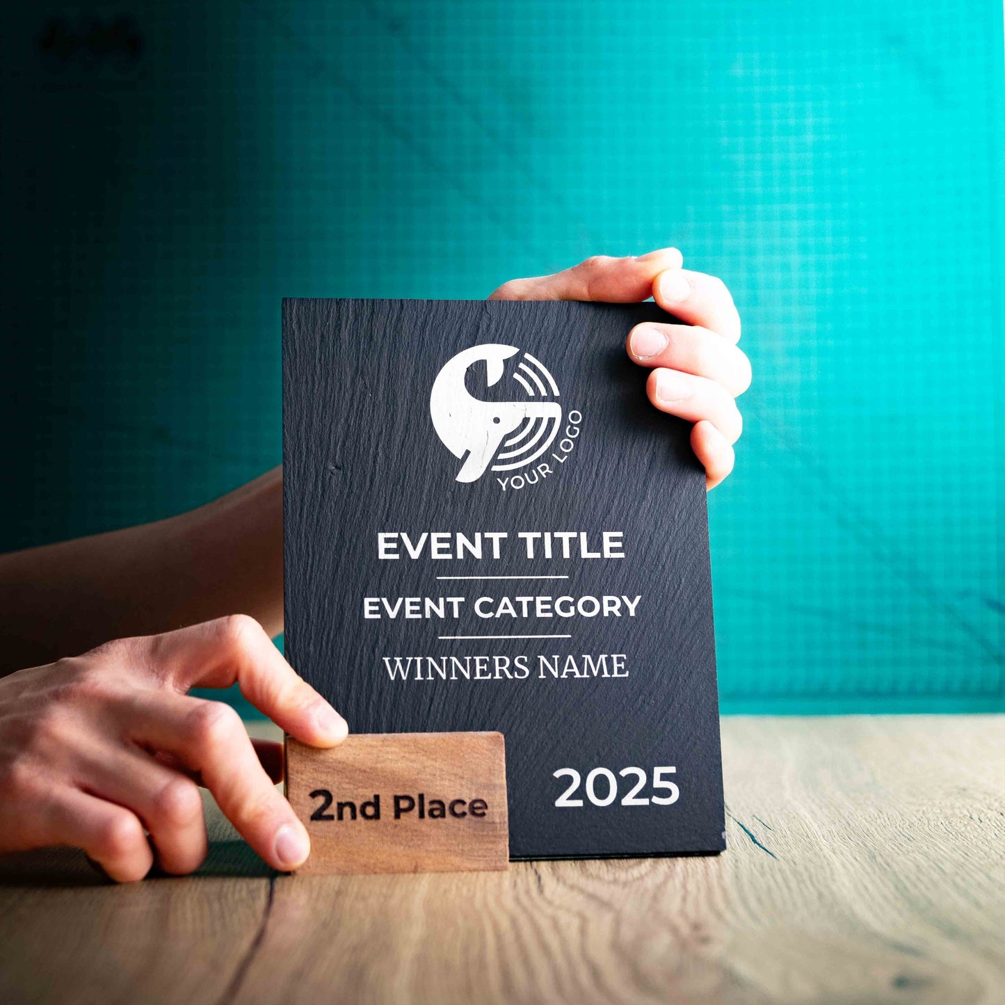 A medium Solet Award, an eco-friendly, wooden and slate trophy. The Solet Award has a base made of two wooden pieces on either side of a square piece of Welsh Slate. The trophy is personalised with Event information and a logo. 