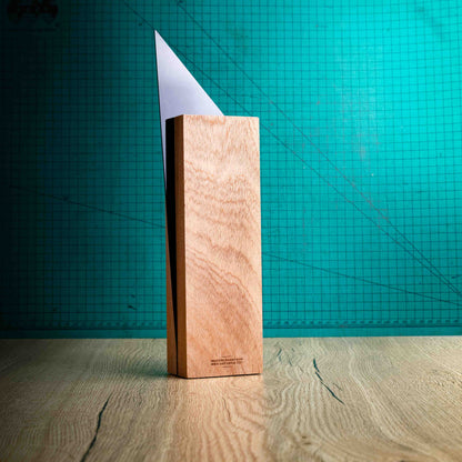 The back of the Spike Award, an Eco-friendly wooden trophy with 'responsibly sourced wood' text and www.lasersareus.com on a wooden surface.