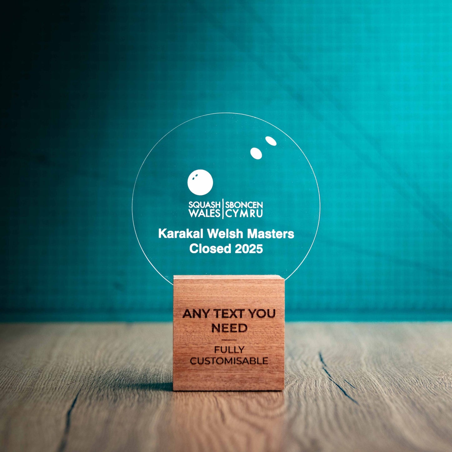 A medium Squash trophy with custom text and logos, on an eco-friendly wooden base, with a clear Perspex Squash ball mounted on top, featuring fully customisable areas for text and logos.