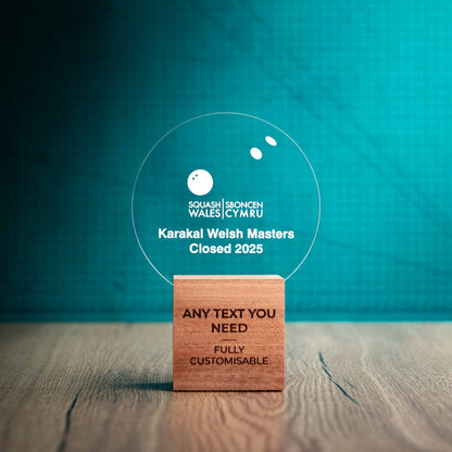 A medium Squash trophy with custom text and logos, on an eco-friendly wooden base, with a clear Perspex Squash ball mounted on top, featuring fully customisable areas for text and logos.