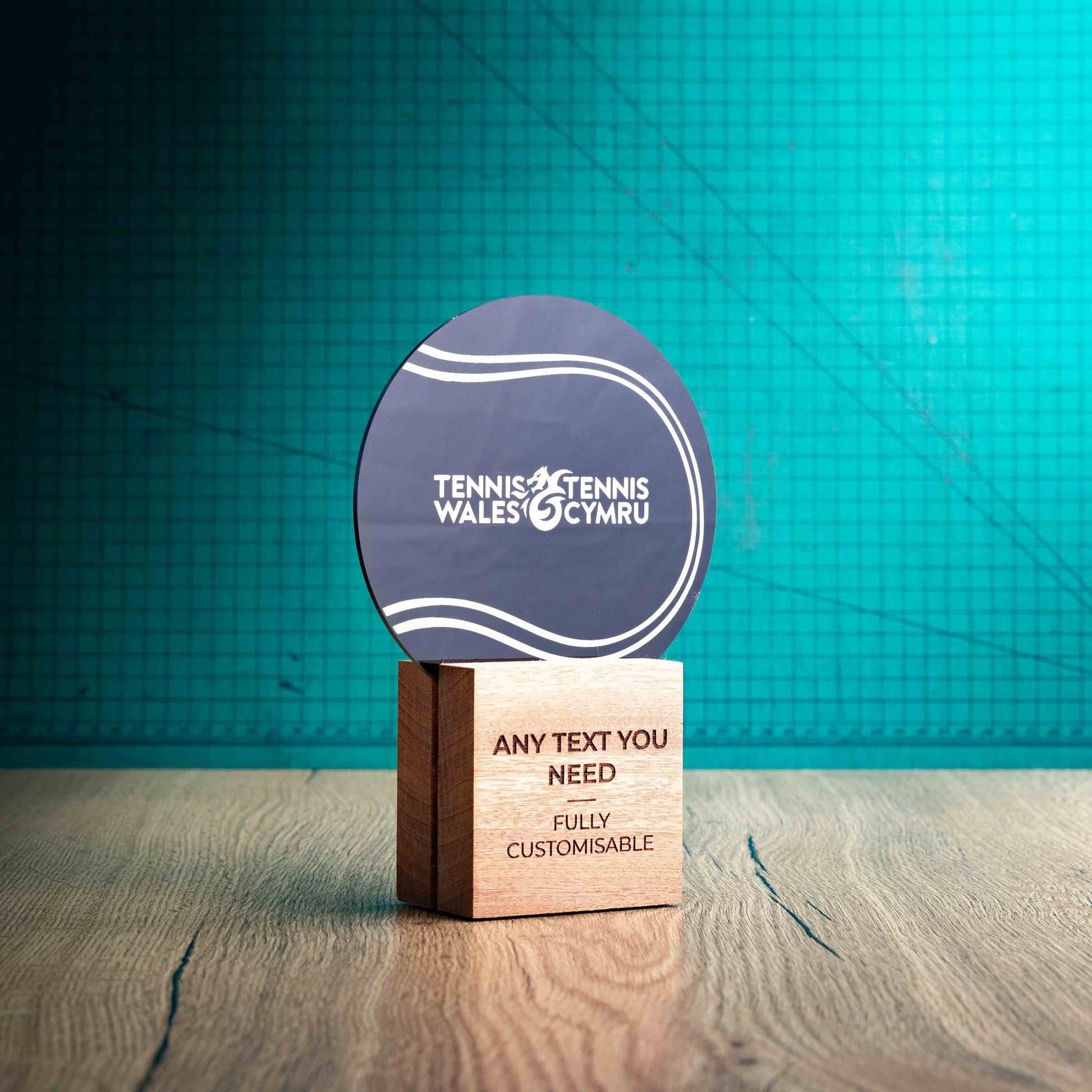 A side view of a medium Legacy trophy with custom text and logos, on an eco-friendly wooden base, with a black Perspex circle mounted on top, featuring fully customisable areas for text and logos.