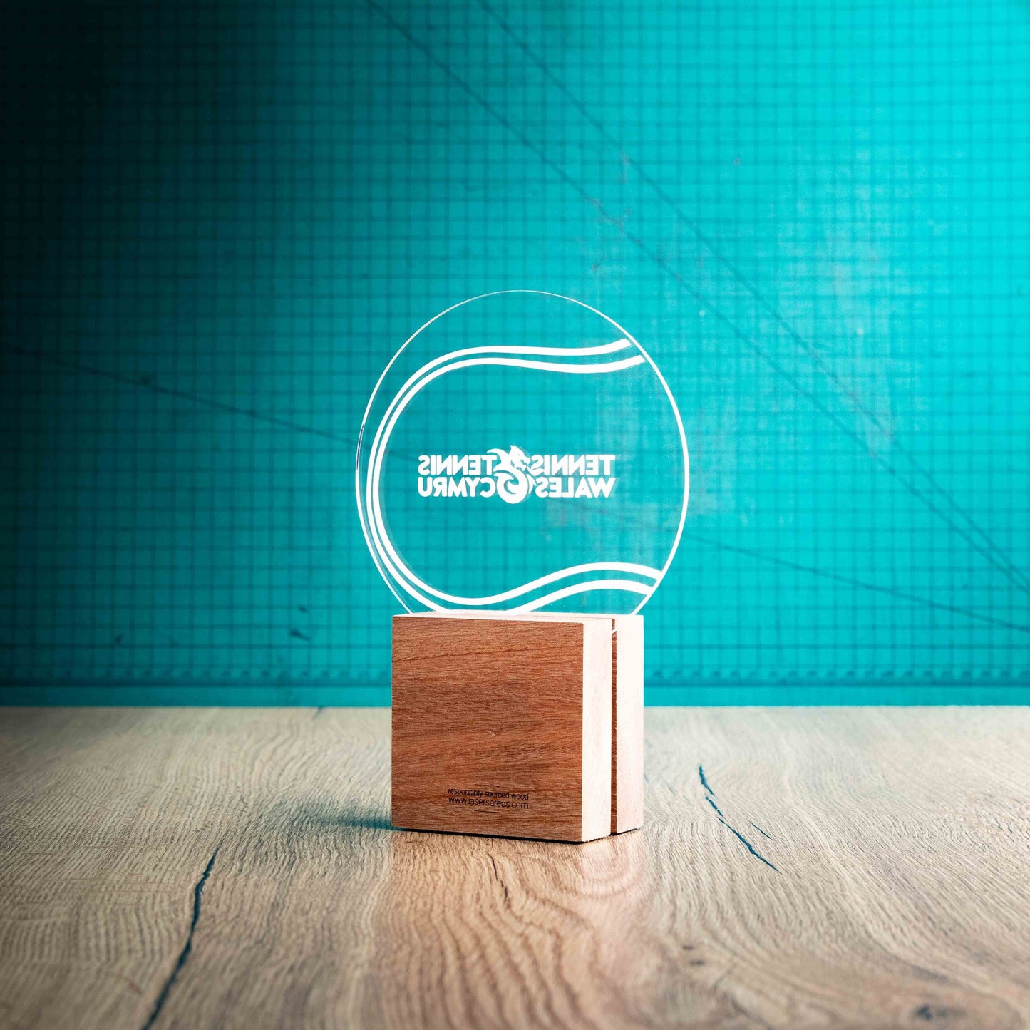 A back view of a medium Tennis trophy with custom text and logos, on an eco-friendly wooden base, with a clear Perspex Tennis ball mounted on top, featuring fully customisable areas for text and logos.