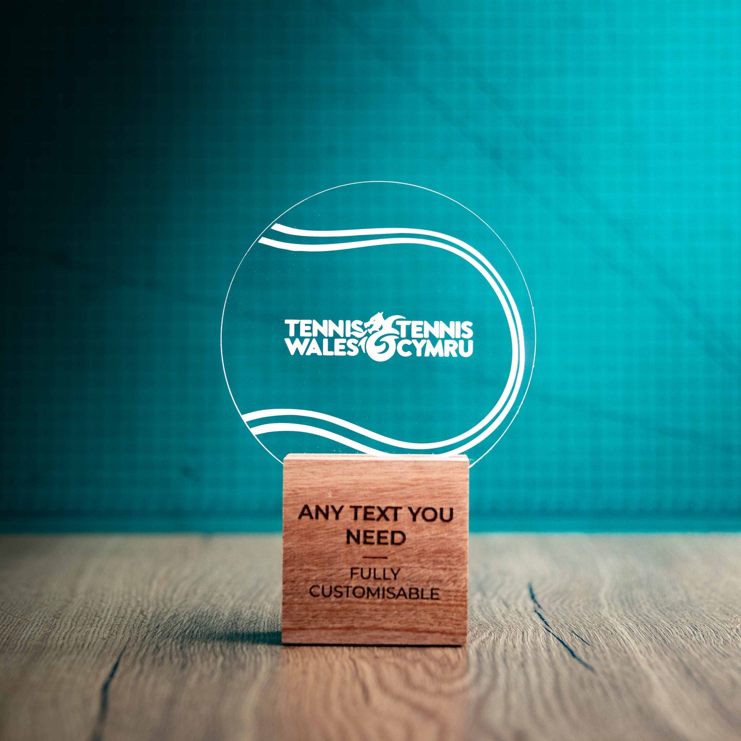 A medium Tennis trophy with custom text and logos, on an eco-friendly wooden base, with a clear Perspex Tennis ballmounted on top, featuring fully customisable areas for text and logos.