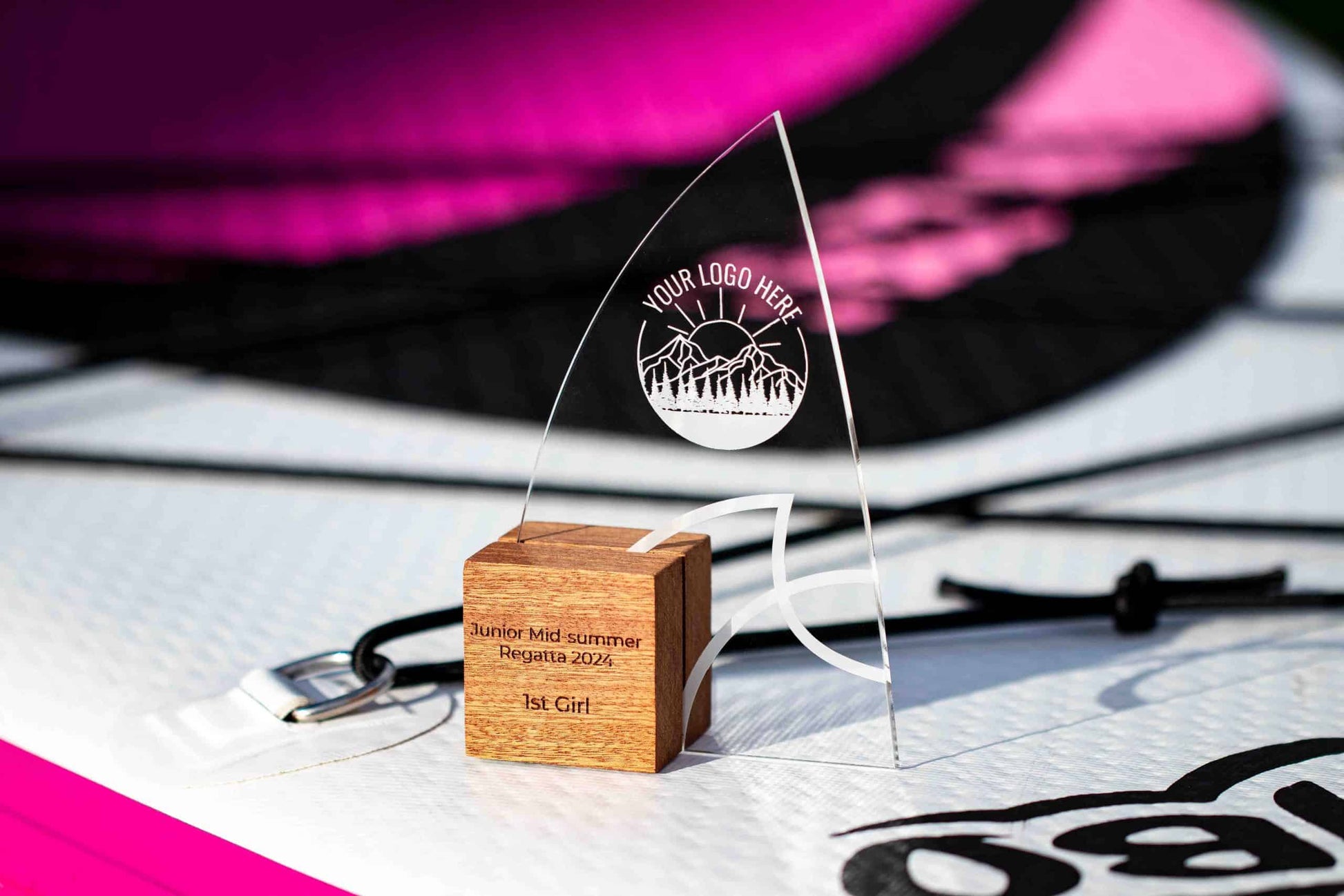 The Windward Award, An Eco-Friendly Wooden Trophy with recycled perspex, sat on a pink and white Paddle Board in the sun