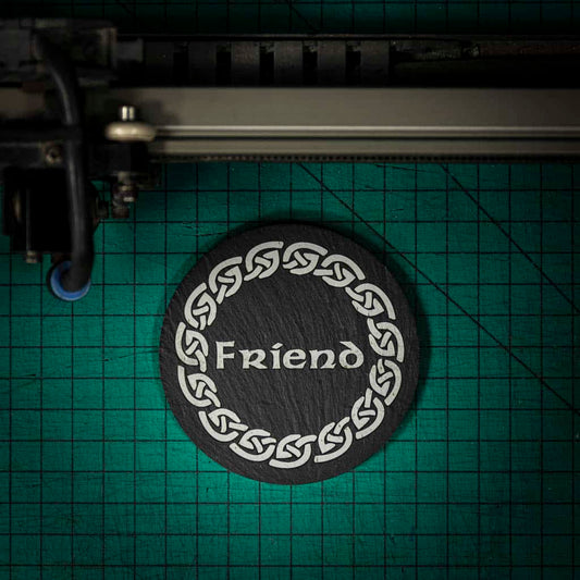 A Welsh slate coaster laser engraved with the word friend inside a celtic knot
