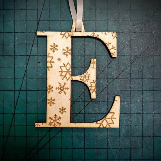 A wooden Christmas tree decoration laser cut into the shape of the letter "E" and engraved with snowflakes