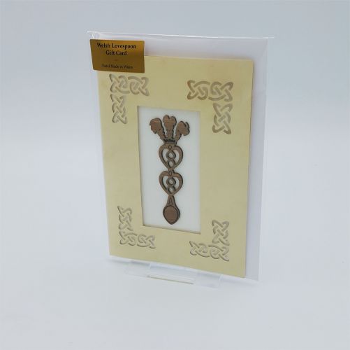 A laser cut card with an affixed wooden lovespoon with three feathers