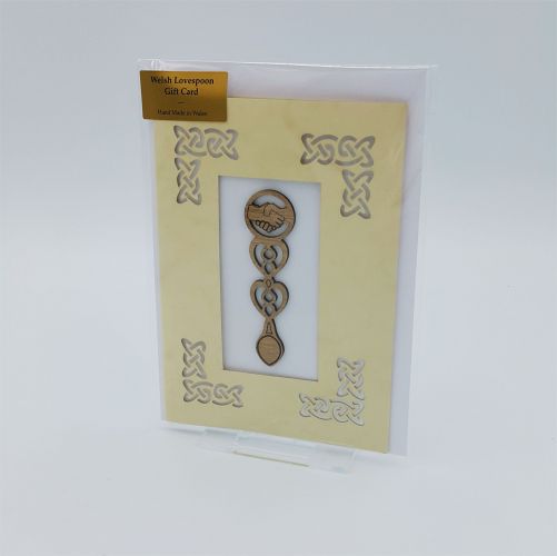 A laser cut card with an affixed wooden lovespoon with shaking hands